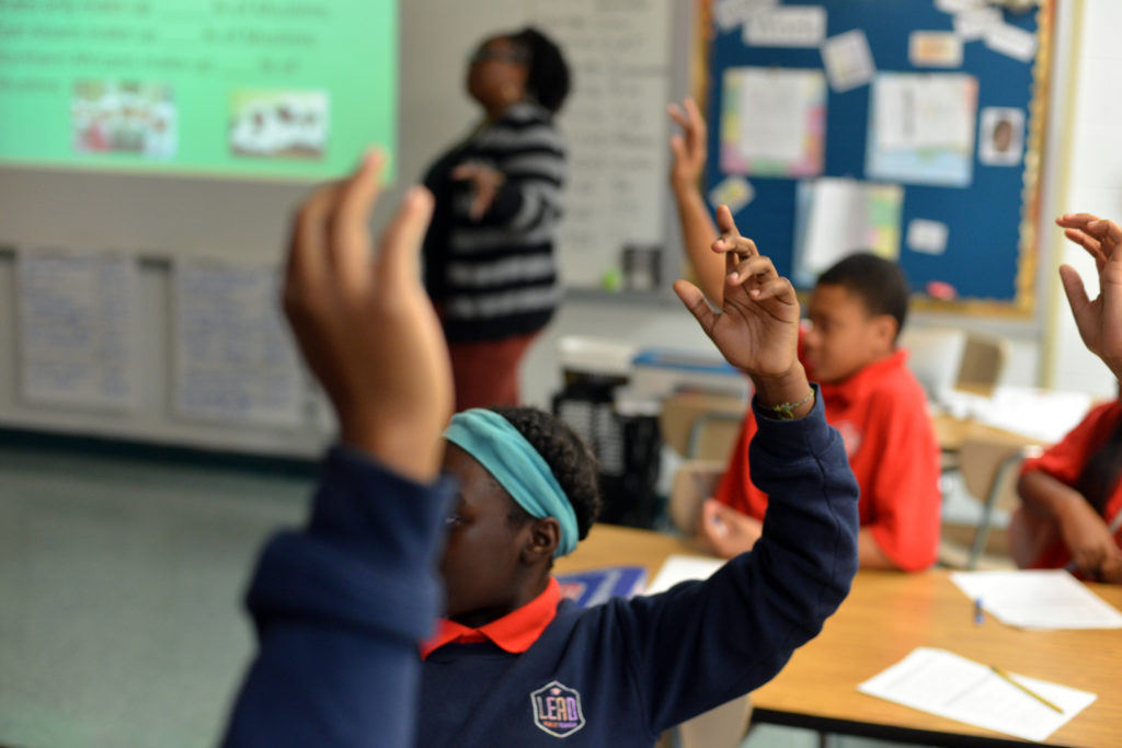 Students raise their hand in an engaged lesson.